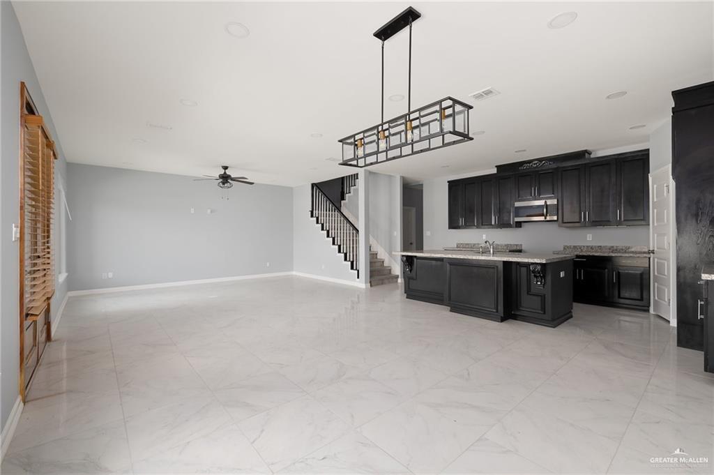 5307 North Crown Point Pharr, TX 78577 - Photo 11 of 11 Kitchen with dark cabinetry, light marble finish flooring, open floor plan, an island with sink, and stainless steel microwave