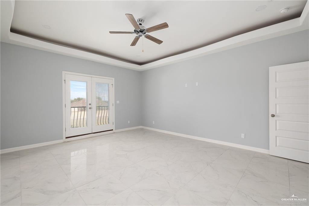 5307 North Crown Point Pharr, TX 78577 - Photo 6 of 11 Spare room with a tray ceiling, french doors, a ceiling fan, and light marble finish floors