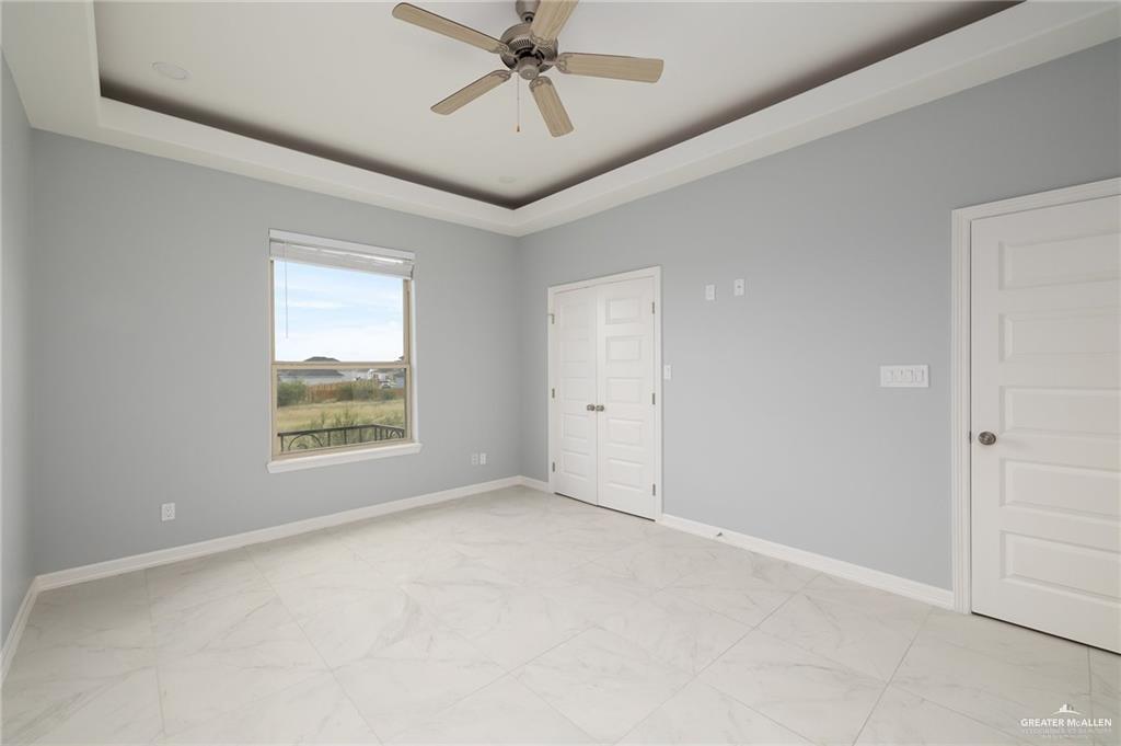 5307 North Crown Point Pharr, TX 78577 - Photo 9 of 11 Unfurnished bedroom with a raised ceiling, ceiling fan, light marble finish floors, and a closet