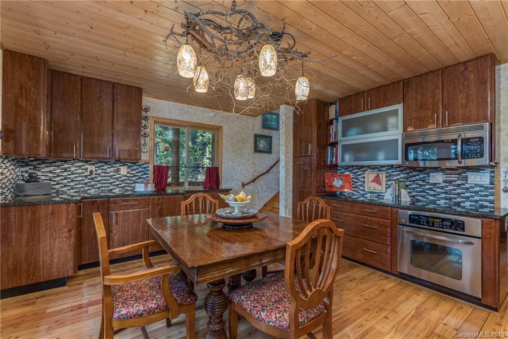185 Caledonia Road Landrum, SC 29356 - Photo 14 of 30 a kitchen with stainless steel appliances granite countertop a stove top oven a sink dishwasher a dining table and chairs with wooden floor