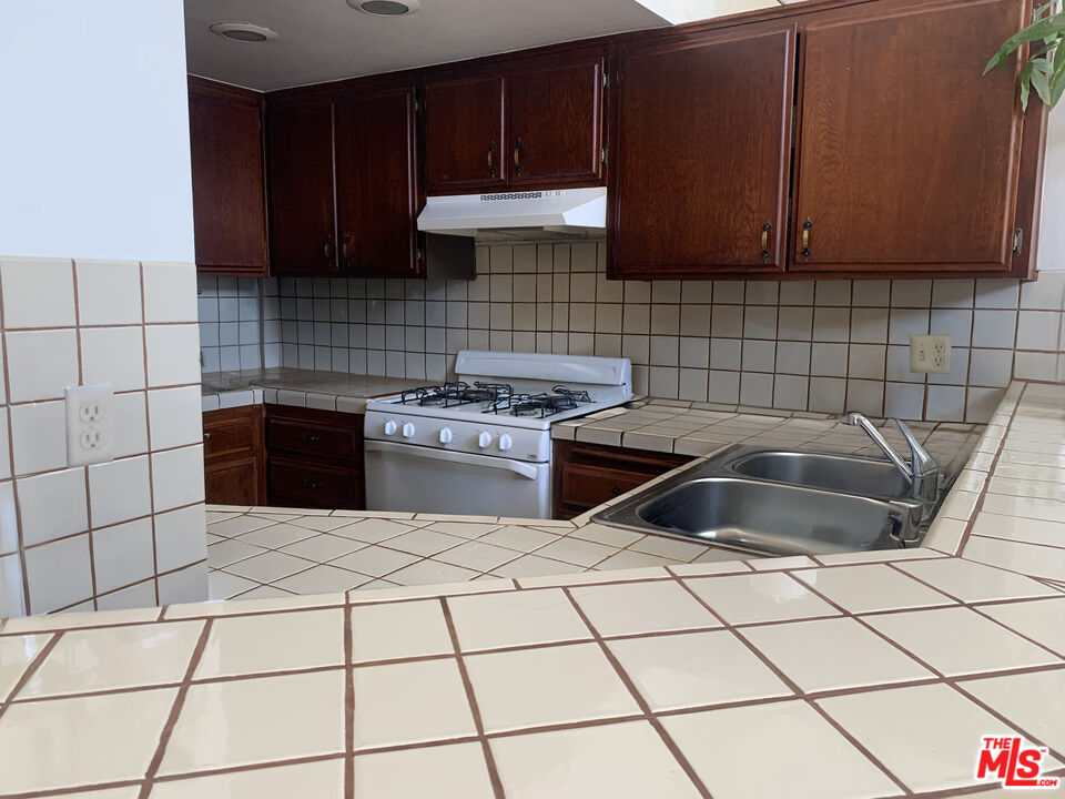 11767 Iowa Avenue, Unit 10 Los Angeles, CA 90025 - Photo 2 of 8 a kitchen with granite countertop a sink a stove a microwave and cabinets