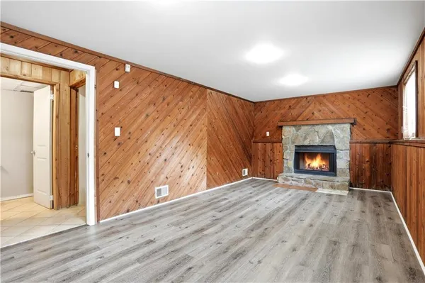 an empty room with wooden floor fireplace and windows