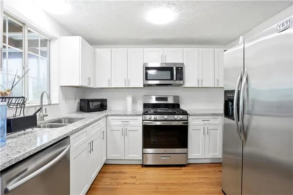 a kitchen with stainless steel appliances granite countertop a stove a sink dishwasher a refrigerator and a microwave