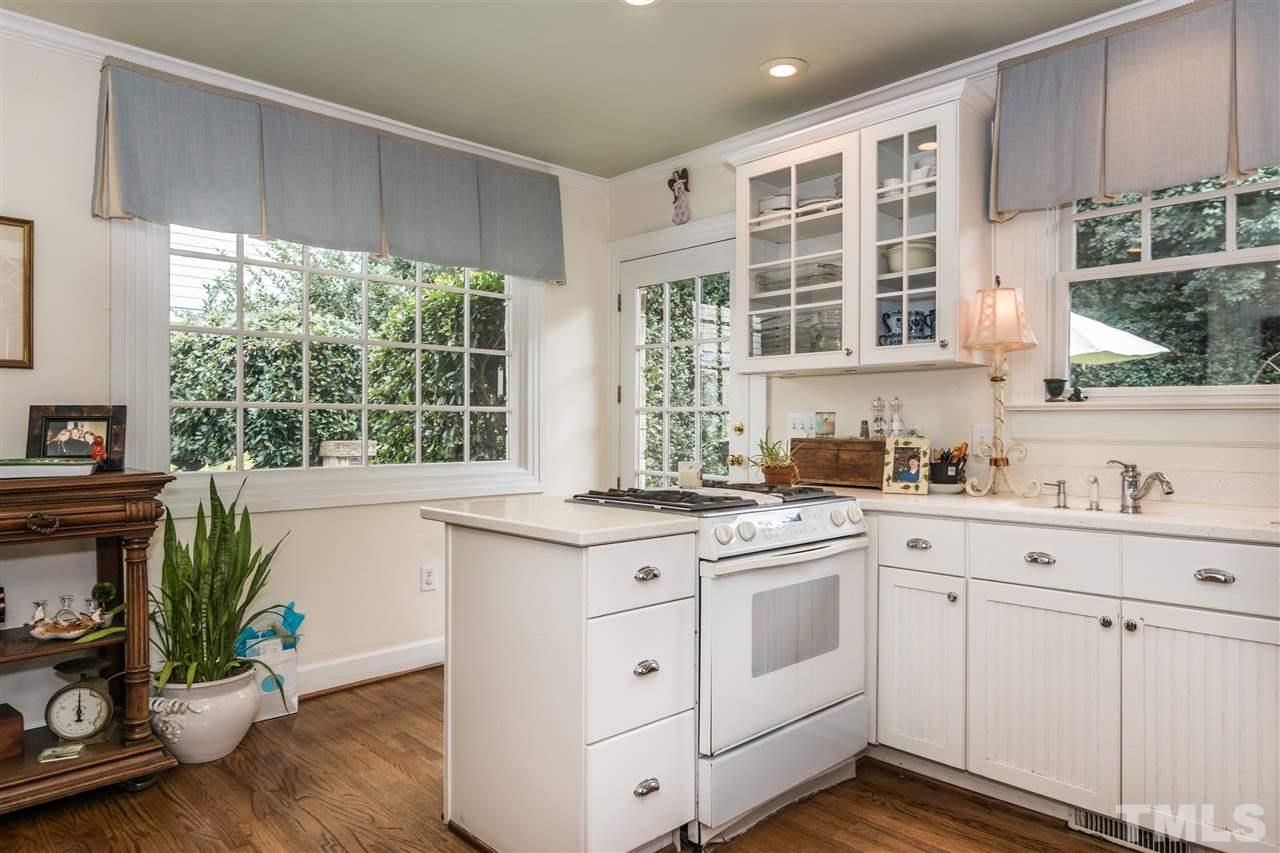 2320 Byrd Street Raleigh, NC 27608 - Photo 13 of 25 a kitchen with a white stove top oven and white cabinets with wooden floor