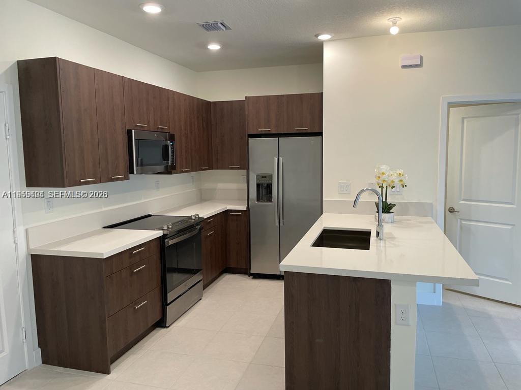 4657 Northwest 83rd Path Doral, FL 33166 - Photo 5 of 23 a kitchen with kitchen island a sink appliances and cabinets