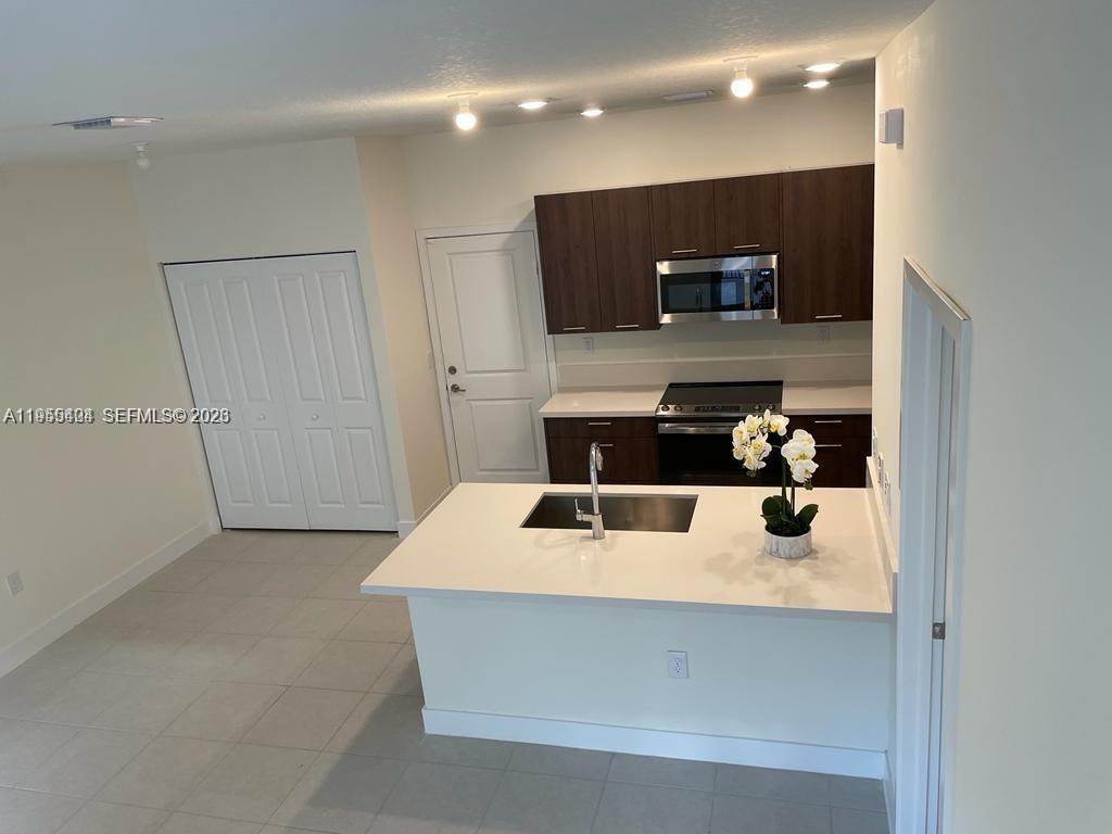 4657 Northwest 83rd Path Doral, FL 33166 - Photo 8 of 23 a kitchen with kitchen island a refrigerator and a sink