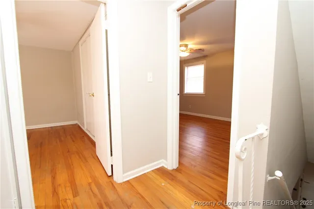 a view of a hallway with wooden floor and a bathroom