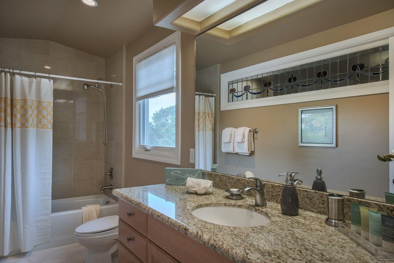 62 Corona Road Carmel, CA 93923 - Photo 24 of 28 a bathroom with a granite countertop sink a toilet a mirror and shower