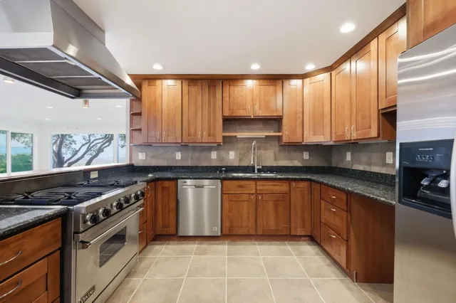 a kitchen with stainless steel appliances granite countertop a stove a sink and a microwave