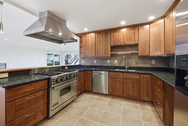 a kitchen with stainless steel appliances granite countertop a stove a sink and a refrigerator