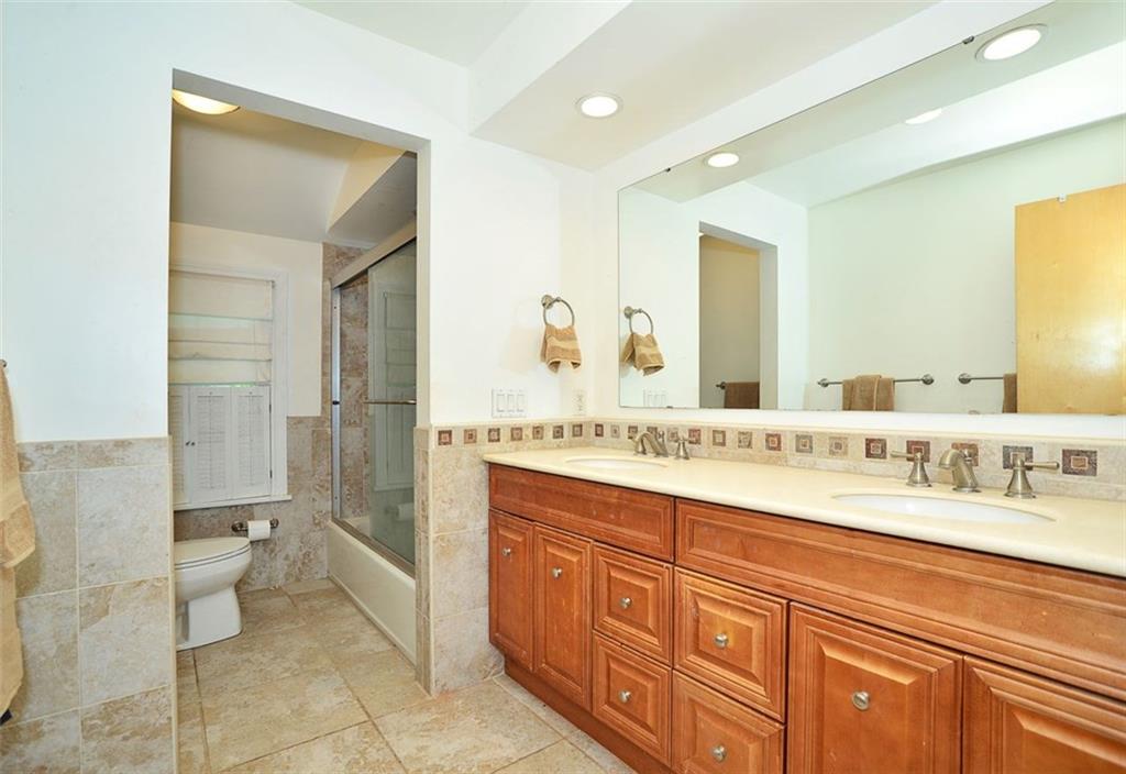 10550 Grubbs Road Wexford, PA 15090 - Photo 18 of 25 Newly remodeled main bathroom offers double sink vanity, large wall mirror newer commode and tub along with newer wall and floor ceramic tile.
