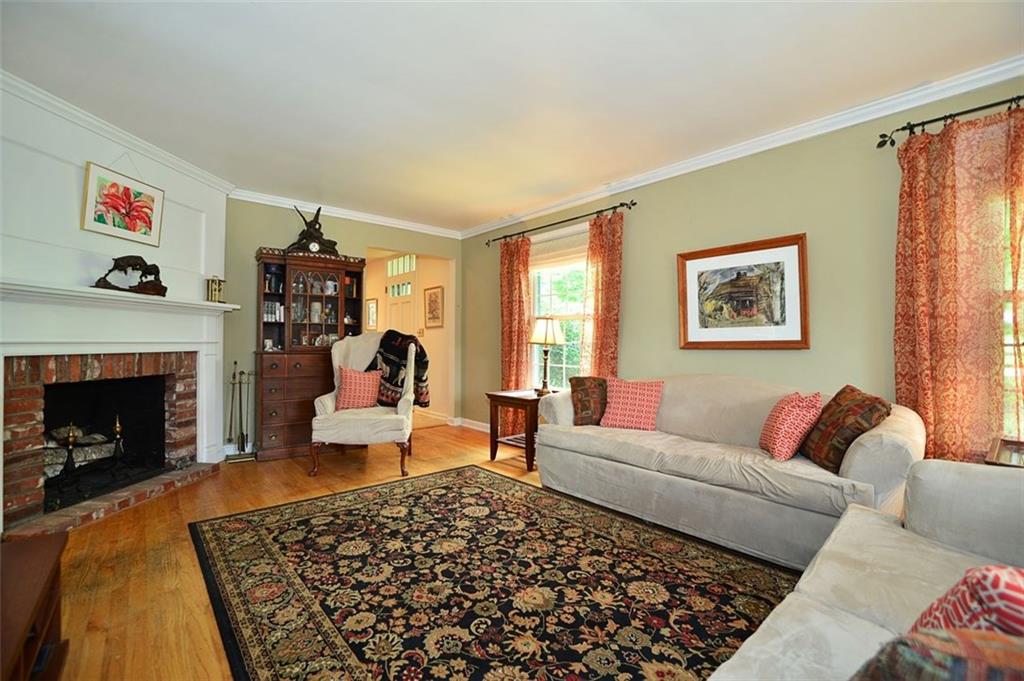 Living room features hardwood floors, tall windows, crown molding and a beautiful and functional log burning fireplace.