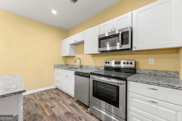 a kitchen with stainless steel appliances granite countertop a stove a microwave and a sink