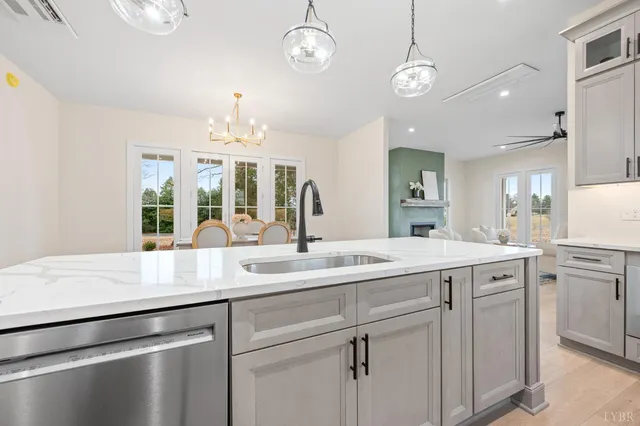 a open kitchen with a sink and dishwasher with white cabinets