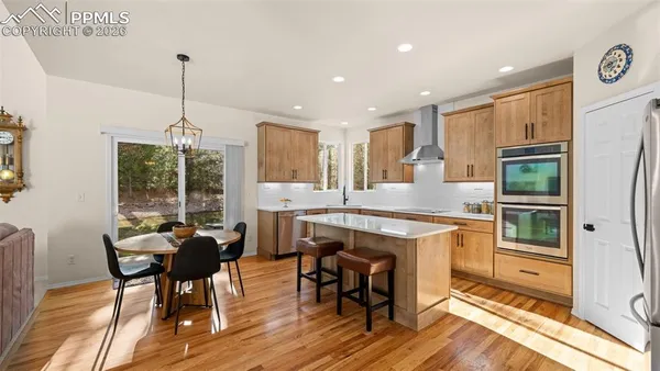 a kitchen with stainless steel appliances granite countertop wooden floor dining table and chairs