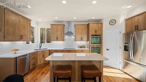 a kitchen with stainless steel appliances a table chairs refrigerator and sink