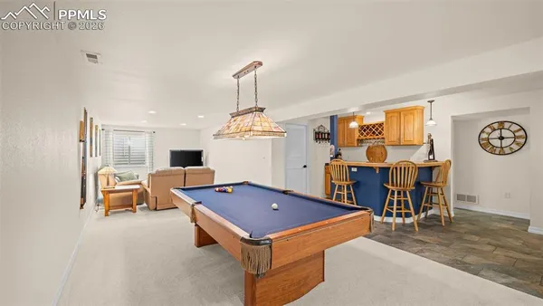 a living room with furniture pool table and chairs