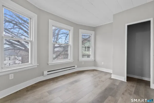 a view of an empty room with a window and wooden floor