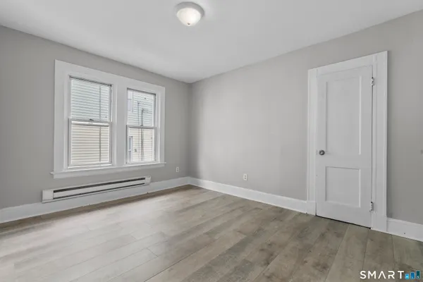 a view of an empty room with wooden floor and a window