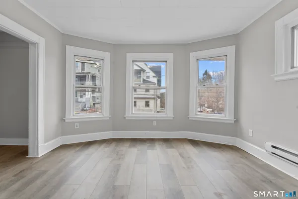 a view of an empty room with wooden floor and a window