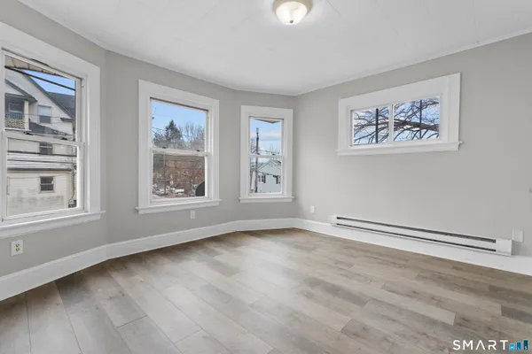 a view of an empty room with a window and wooden floor