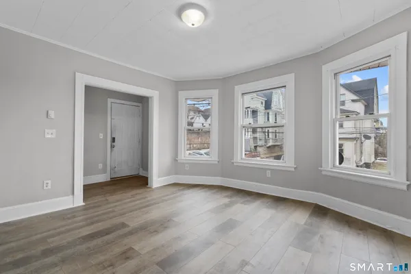 a view of an empty room with wooden floor and windows