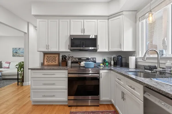 a kitchen with granite countertop a stove a sink and a microwave