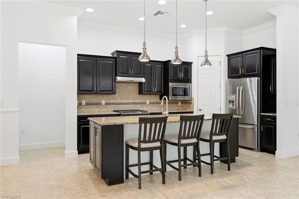 9436 Whooping Crane Way Naples, FL 34120 - Photo 4 of 32 a kitchen with stainless steel appliances kitchen island a refrigerator and a stove top oven
