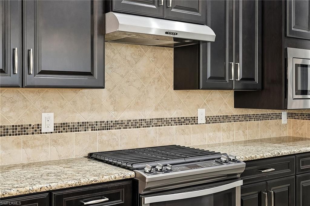 9436 Whooping Crane Way Naples, FL 34120 - Photo 5 of 32 a kitchen with granite countertop a stove and a sink