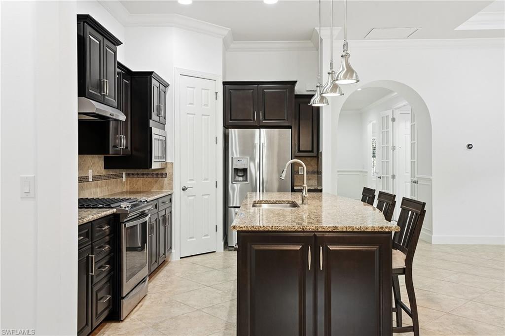 9436 Whooping Crane Way Naples, FL 34120 - Photo 6 of 32 a kitchen with stainless steel appliances granite countertop a sink stove and refrigerator