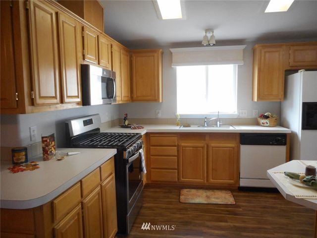 a kitchen with stainless steel appliances granite countertop a sink a stove cabinets counter space and a window