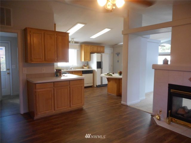 a kitchen with granite countertop a stove top oven a sink dishwasher and a fireplace with wooden floor