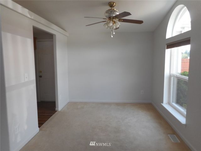 an empty room with a window and a fan