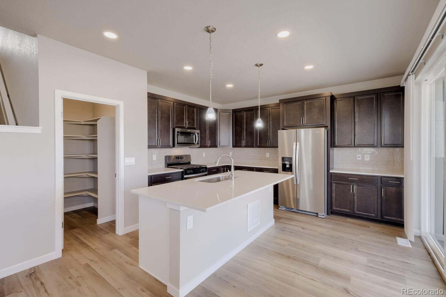 471 Atchison Way Calhan, CO 80808 - Photo 13 of 31 a large kitchen with stainless steel appliances kitchen island a large counter top and a refrigerator