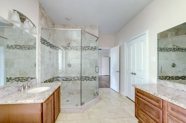 a spacious bathroom with a granite countertop sink mirror and shower
