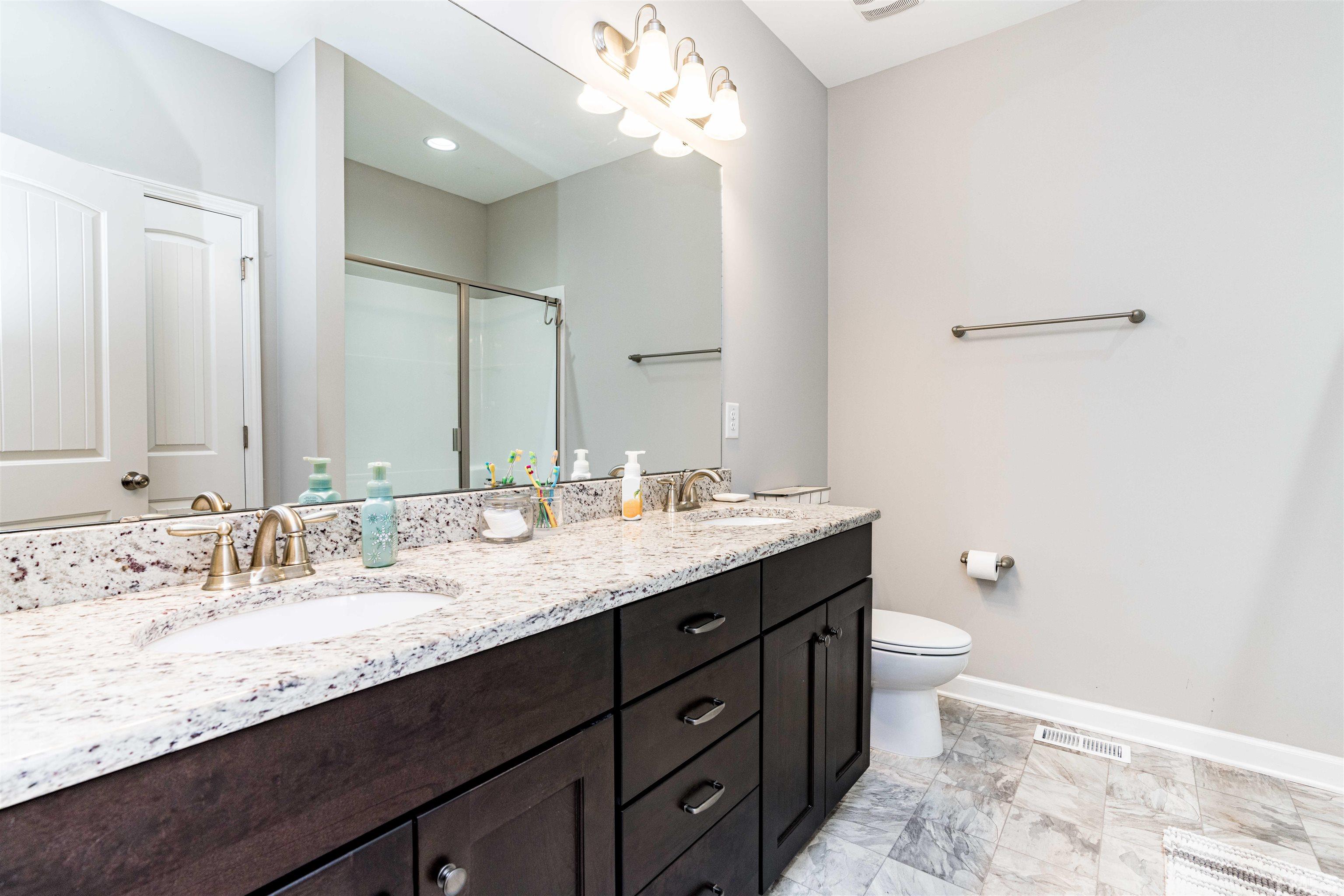 11565 Barnes Road Middlesex, NC 27557 - Photo 14 of 25 a bathroom with a granite countertop sink a toilet and a mirror