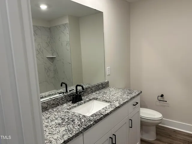 a bathroom with a granite countertop sink and a toilet