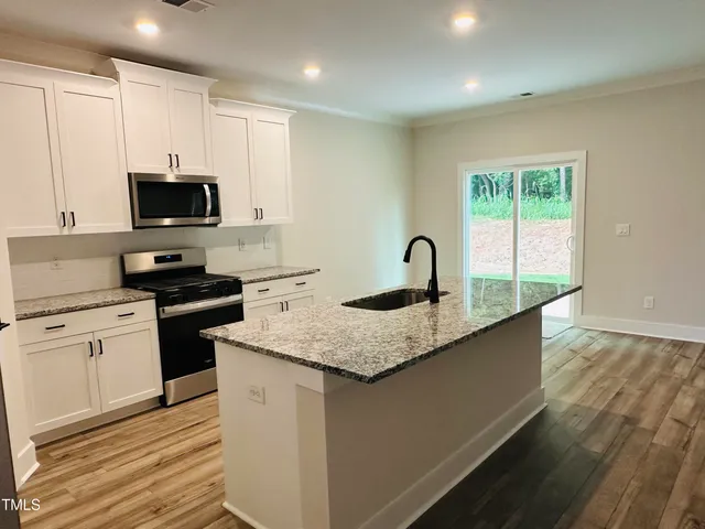 a kitchen with granite countertop a sink and a stove top oven