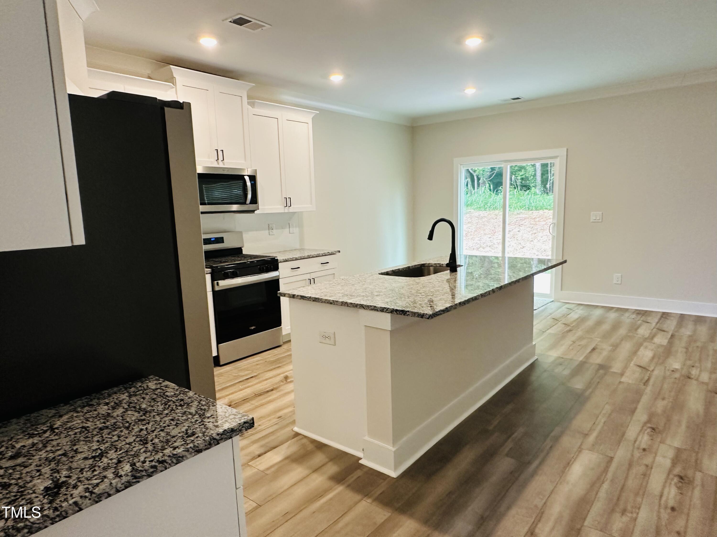 306 Shiloh Way Mebane, NC 27302 - Photo 7 of 33 a kitchen with stainless steel appliances granite countertop a sink a stove a refrigerator a washer dryer and white cabinets