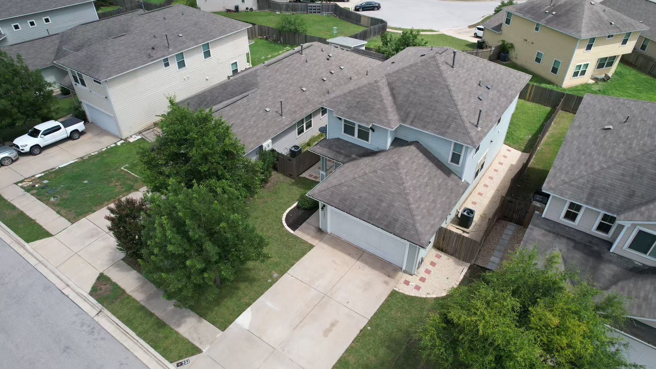 251 Triumph Road Buda, TX 78610 - Photo 22 of 26 An aerial perspective showcases a two-story residence with a paved driveway and an attached garage.