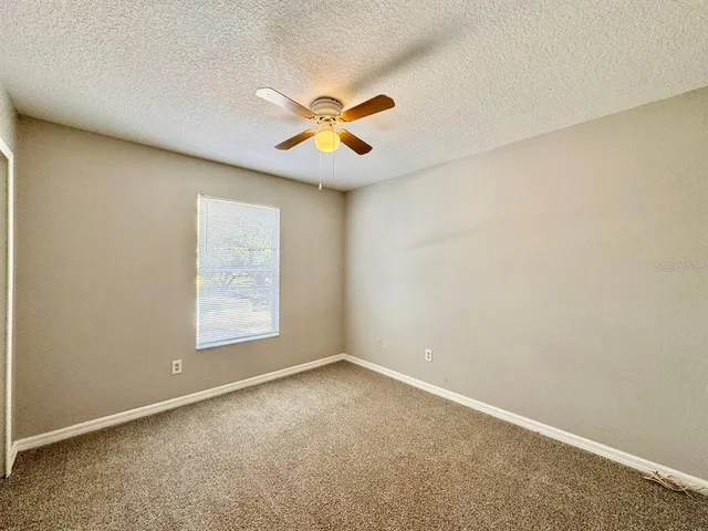 an empty room with windows and fan