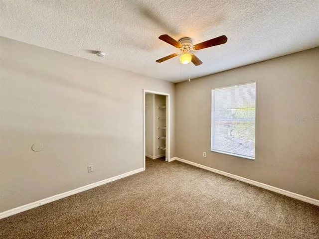 an empty room with windows and fan