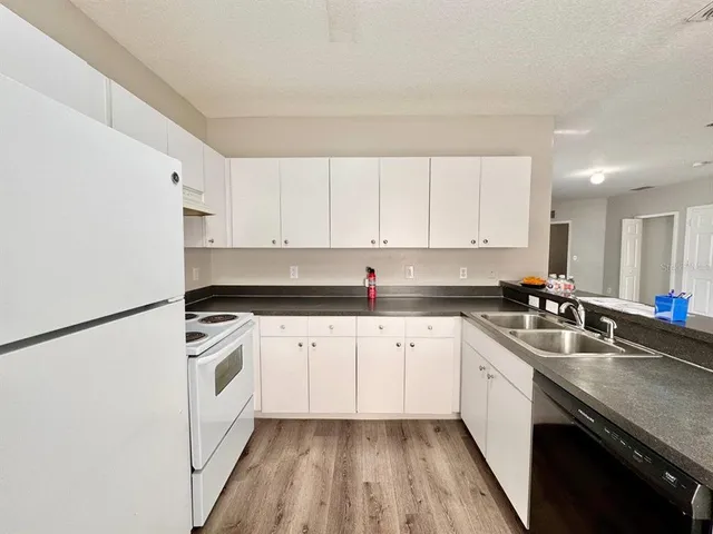 a kitchen with granite countertop white cabinets sink and white appliances