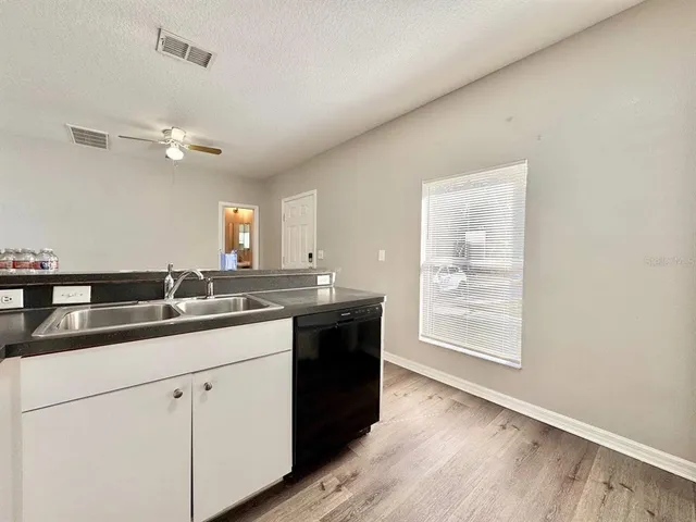 a kitchen with a sink dishwasher and a stove with wooden floor