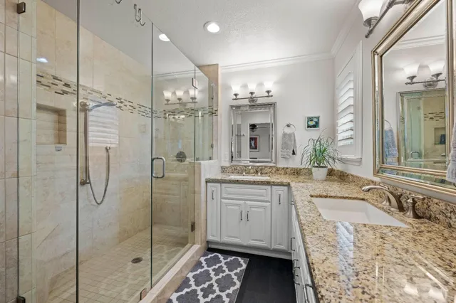 a bathroom with a granite countertop sink a mirror a bathtub and shower