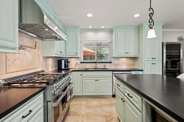 a kitchen with stainless steel appliances granite countertop a sink a stove and a refrigerator