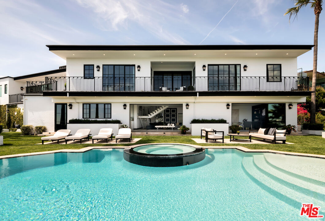 a front view of a house with swimming pool and chairs