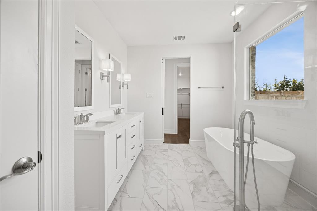 1317 Benjamin Trail Van Alstyne, TX 75495 - Photo 12 of 29 a spacious bathroom with a double vanity sink a large mirror and a bathtub