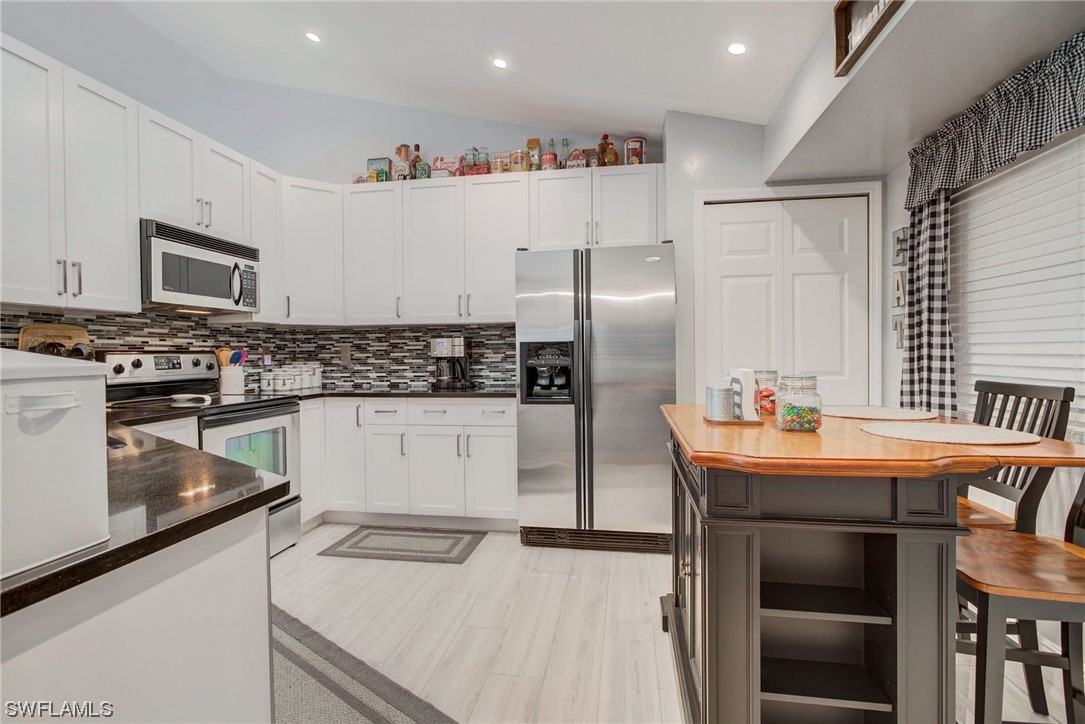 8337 Robin Road Fort Myers, FL 33967 - Photo 13 of 36 a kitchen with stainless steel appliances granite countertop a refrigerator a stove and a sink with wooden floor