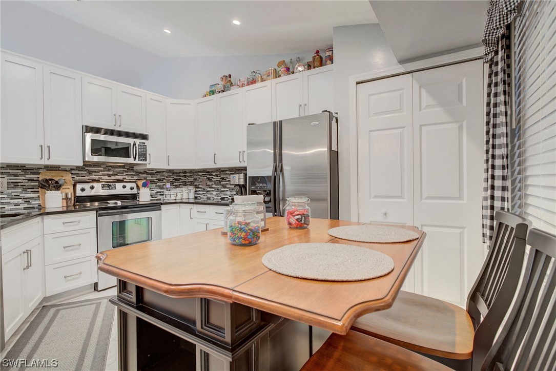 8337 Robin Road Fort Myers, FL 33967 - Photo 14 of 36 a kitchen with stainless steel appliances granite countertop a sink a stove a refrigerator with a dining table and chairs